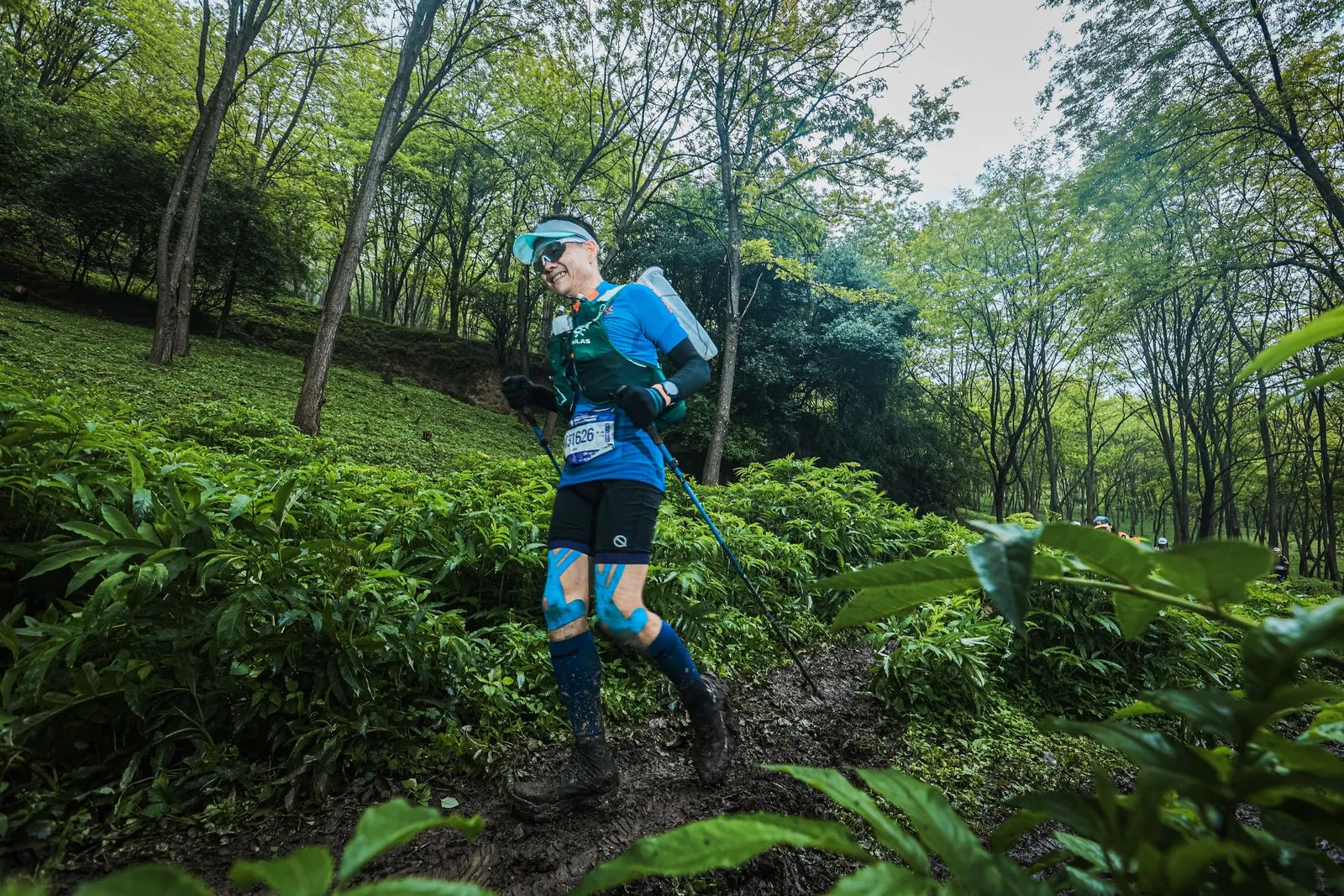 Athlete running through scenic forest trail during a daytime race.